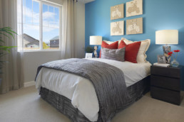 A bedroom featuring a blue wall with motorcycle artwork and a grey bedspread.