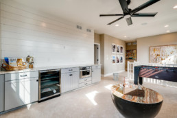 A family room featuring a wine cooler and bar counter top with a Foosball table.