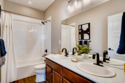 A new bathroom with double sinks, a large bathtub and shower and modern faucets.