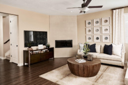 A modern family room with plush couch, large TV and a fireplace.