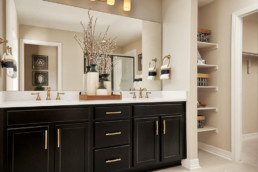 A large bathroom vanity with dark cabinetry, a white countertop and double sinks.