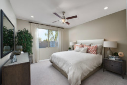 A beautiful new bedroom with a large bed, ceiling fan and a large window.