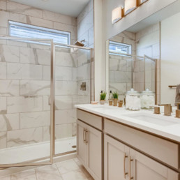 A modern bathroom with a large shower and vanity with double sinks.
