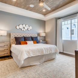 A large bedroom with a feature wall, contemporary artwork and a large bed with throw pillows.