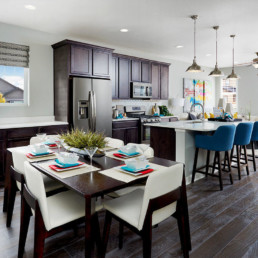 A brand new colorfully decorated dining room and kitchen featuring dark cabinetry.