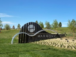 The Harmony entry feature among green grass, new trees and a freshly planted garden.